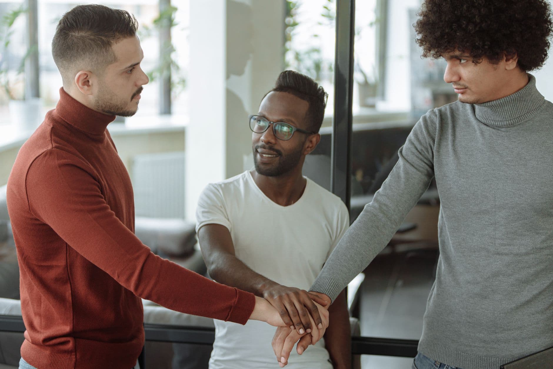 Três profissionais diversos colaborando em equipe em ambiente corporativo moderno, fortalecendo a confiança no trabalho